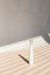 White eco hygiene lipstick in striped shadow gray background.