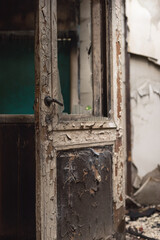 Old dilapidated door with peeling paint in a dilapidated building.