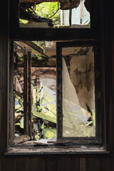 Old dilapidated window frame with broken glass inside an old abandoned building.