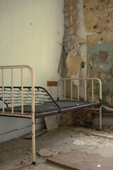 Old hospital bed in an abandoned and dilapidated dirty room.