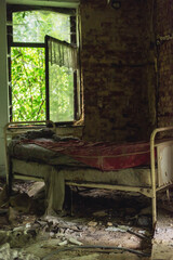 Fototapeta na wymiar Old hospital bed in an abandoned and dilapidated dirty room with an open window.