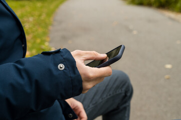 Close-up of the phone in the hands of a man. Autumn Park.