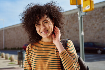 Smiling young woman touching her hair outdoors