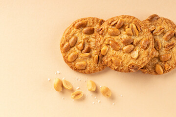 Cookies with roasted peanuts on top on beige background. View from above. Place for text.