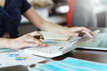 Businesswoman working from home with a calculator and financial report on wooden table.