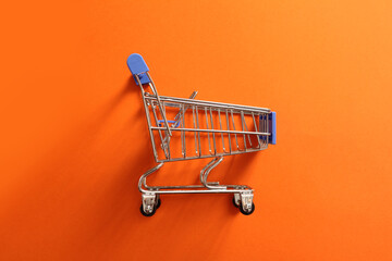 shopping cart, empty grocery cart on orange background © irinad85