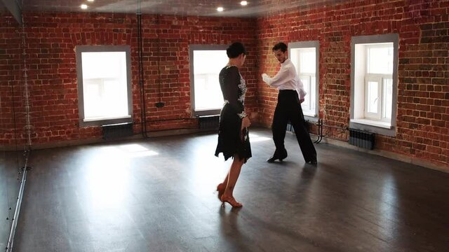An attractive couple training dancing elements in the room