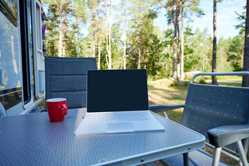 Mobilework Homeoffice aus dem Urlaub in der Ferne mit dem Laptop und einem Wohnmobil Wohnwagen