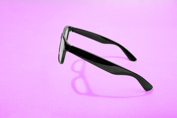 flying black glasses with shadow on pink background.