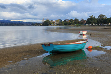Small boats resting on the sand on the edge of the sea, Tauranga Harbour,  New Zealand