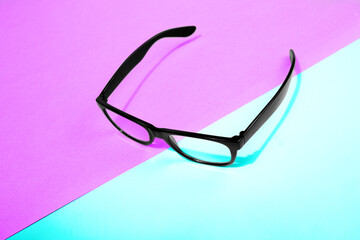 flying black glasses with shadow on pinkon a blue background.