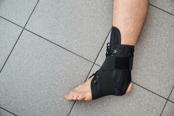 The male leg is fixed in a medical bandage. Ankle fracture or sprain. Lacing and tight fit of the...