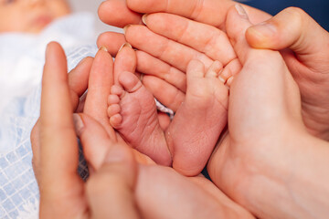 winzige Füße eines Neugeborenen in den Händen liebevoller Eltern