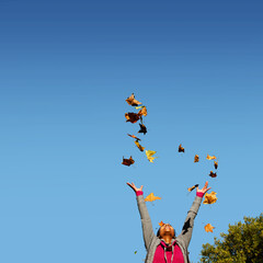 Junge Frau wirft Herbstlaub in den blauen Himmel, Hannover, Niedersachsen, Deutschland