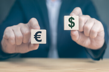 Currency concept. businessman's hands hold two wooden cubes with dollar and euro sign. businessman chooses euro or dollar signs