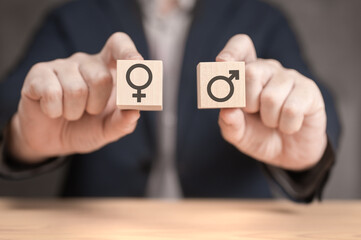 choice between man and woman. hands hold two wooden cubes with male and female sign. equality and differences between men and women. Gender icon on wooden blocks. person holding gender symbols - obrazy, fototapety, plakaty