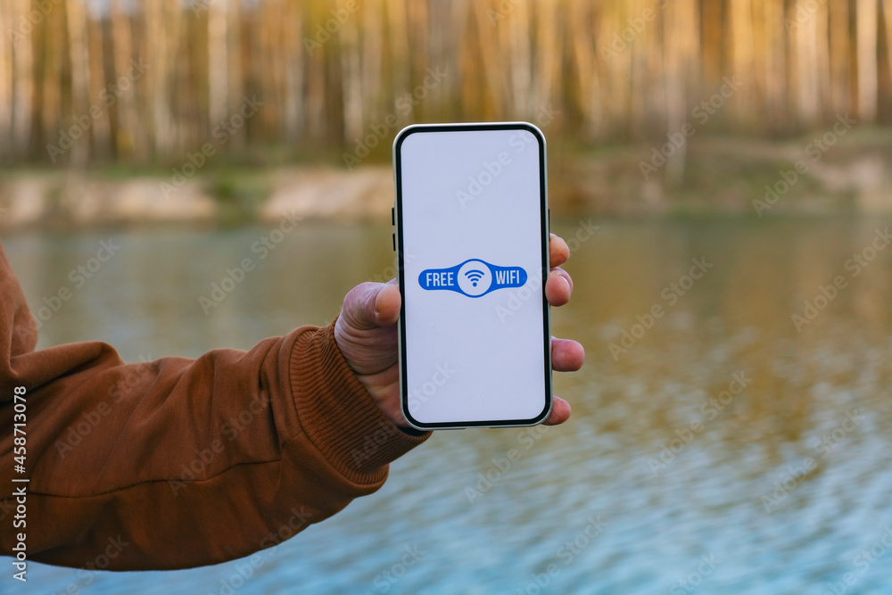 Poster man holds a smartphone in his hand with a free wi-fi icon on the display. phone on the background of