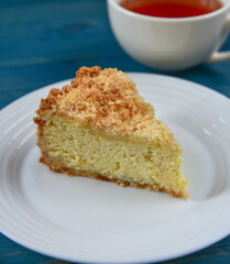 An appetizing piece of sweet cottage cheese pie on a white plate on a blue wooden background