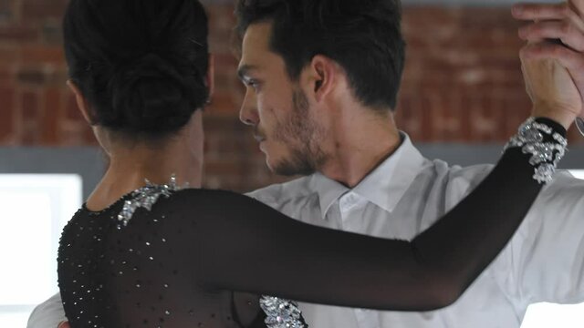 Man and woman practicing latina sensual dancing in the studio with brick walls