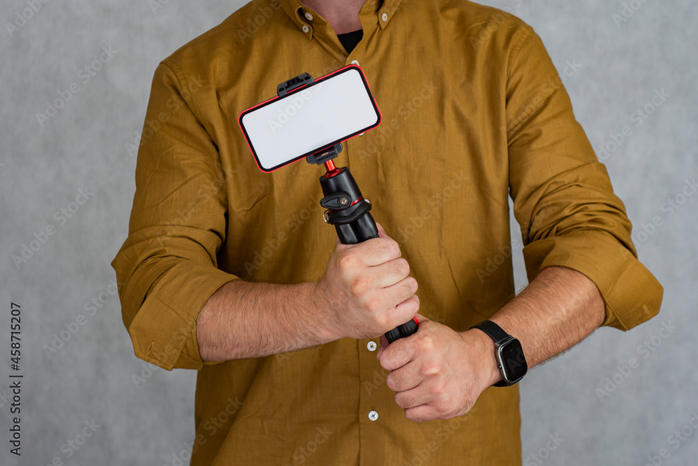Aufkleber a man holds a flexible tripod with a mock-up of a smartphone with a white screen.