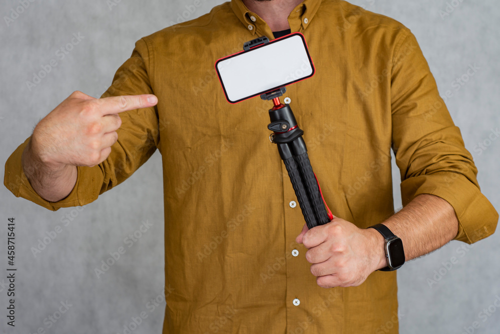 Aufkleber a man holds a flexible tripod with a mock-up of a smartphone with a white screen.