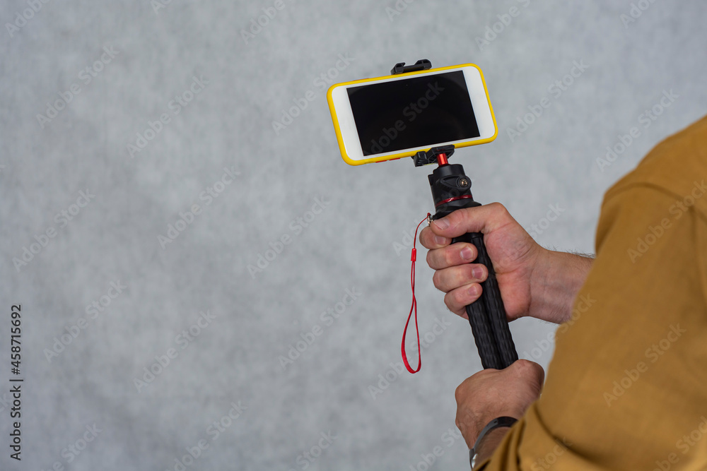 Aufkleber a man holds a flexible tripod with a mock-up of a smartphone with a black screen.