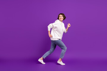 Fototapeta na wymiar Full size profile side photo of young good mood girl running away playful humorous isolated on purple color background