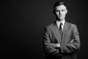 Young businessman wearing suit against gray background