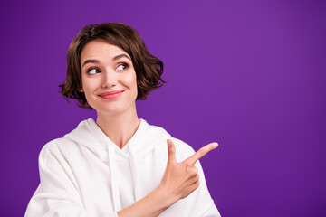 Photo of young dreamy good mood girl recommend product point finger copyspace isolated on violet...