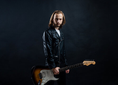 music festival. bearded rocker in leather jacket. man long hair play bass guitar.