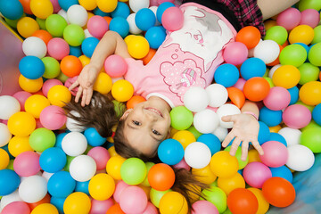 Fototapeta na wymiar a girl is lying on a children's playground in colorful balloons