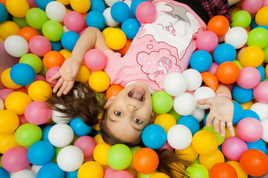 a girl is lying on a children's playground in colorful balloons