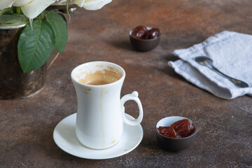An elegant white cup of just brewed espresso with traces of drunk coffee, beautiful little bowls of...