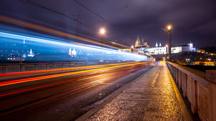 Fototapeta na wymiar Night tram in Prague. Motion blurred tram on Manes Bridge with illuminated Prague Castle on background. Prague, Czech Republic