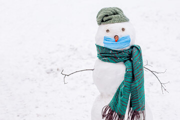 Funny snowman in protective medical mask on white background. Christmas background during...