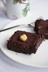 Brownies, Stückchen Brownies mit Schokolade und Haselnuss auf weißem Teller - pieces of brownies with chocolate and hazelnut on white plate