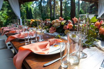 Table served for wedding  Preparing for an open-air party. Decorated with fresh flowers and fruit. Decoration Details. Close up detail of served table in outdoor restaurant.