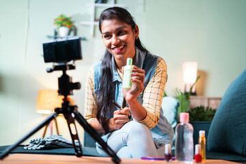 young Indian girl reviews make up cosmetic product to fans on her channel by recording video,...