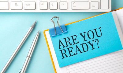 ARE YOU READY text on sticker on the blue background with pen and keyboard