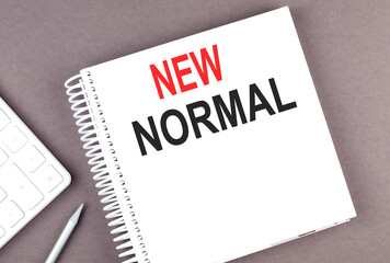 NEW NORMAL text on notebook with calculator and pen,business