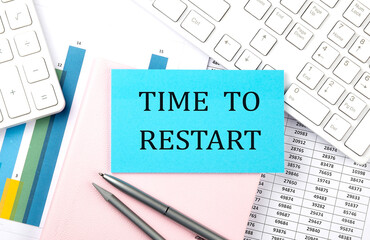 Obraz premium TIME TO RESTART text on blue sticker on chart with calculator and keyboard,Business