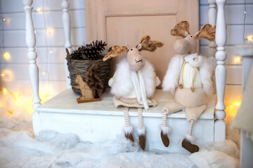 Two funny toy moose, in white fur coats and scarves