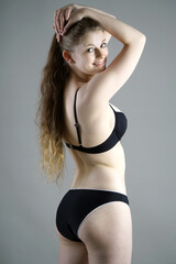 Beautifuly slim teenage girl posing in black bikini in studio