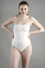 Beautiful slim woman posing in white one piece swimsuit in studio