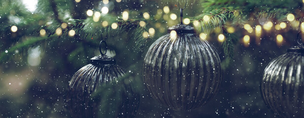 Old silver christmas baubles at fir tree with golden lights and snowflakes. Horizontal background...