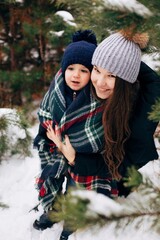 Mom and little son in the winter forest. Older sister and little brother hug. Winter day in the woods
