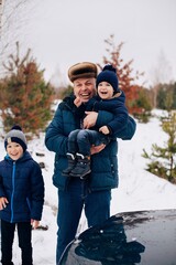 Fototapeta na wymiar Dad with two sons in the winter forest 