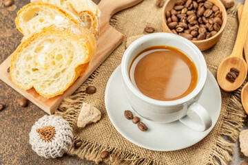 Breakfast concept with a cup of coffee, croissants, milk jug, and decorative crochet pumpkins