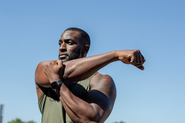 Mid adult man stretching under blue sky