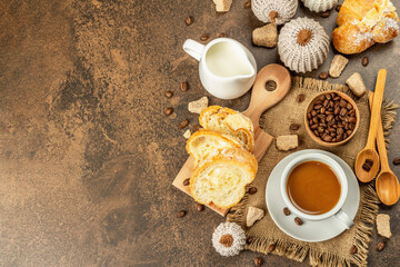 Breakfast concept with a cup of coffee, croissants, milk jug, and decorative crochet pumpkins